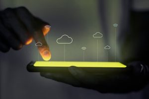 A hand is holding a smartphone with cloud icons on it.