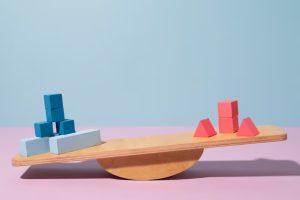A set of wooden blocks on a seesaw on a pink background.